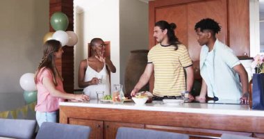 Arkadaşlar mutfakta birlikte yemek hazırlıyor, gülümsüyor ve sıradan toplantıların tadını çıkarıyorlar. Arkadaşlık, yemek pişirme, sosyalleşme, yurt içi, yemek hazırlama, kahkaha