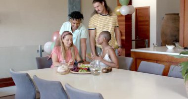 Partide, arkadaşlar evde atıştırmalık ve içeceklerle masanın etrafında sohbet etmekten zevk alıyorlar. Arkadaşlık, kutlama, sosyalleşme, içecekler, rahatlama, rahatlama