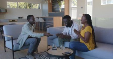 Afro-Amerikalı arkadaşlar kahve masası eşyasıyla modern evde doğum gününü kutluyorlar. Parti, toplantı, dostluk, kutlama, neşeli, rahat, modern, diyalog, içecekler