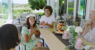 Gelin jestleriyle pasta ve çay ikram ederken verandadaki çeşitli bayan arkadaşlar gelin partisini kutluyorlar. Kutlama, dostluk, açık hava, çiçek, zarafet, sağlık, mutluluk.