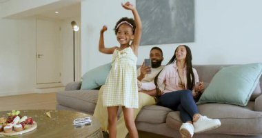 Çeşitli aileler oturma odasında doğum günlerini kutluyor. Keklerin yanında akıllı telefon tutan dansçı kızlar. Kutlama, aile, neşe, birliktelik, konfor, şenlik, modern, etkileşim, mutluluk