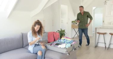 Üst düzey çiftler oturma odasında geziye hazırlanırken pasaportlarını ve şapkalarını paylaşıyorlar. Seyahat, macera, yaşam tarzı, kompakt, rahatlama, ev, modern