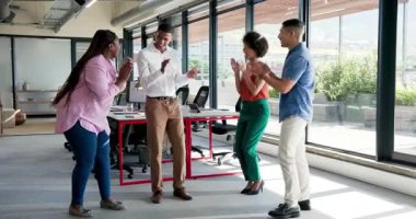 Modern ofis ortamında kutlama yapan çeşitli iş arkadaşları dizüstü bilgisayar ve bitkilerin yanında gülümseme paylaşıyorlar. Kutlama, takım çalışması, işbirliği, katılım, çalışma alanı, üretkenlik, pozitiflik