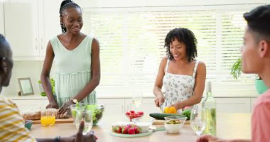 Parlak modern mutfakta kutlama yapan arkadaşlar, kadehleri kaldırmak ve taze salata malzemelerini doğramak. Kutlama, mutfak, toplanma, mutfak, tazelik, canlılık, arkadaşlık.