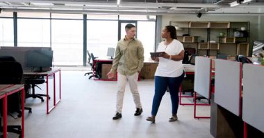 Çeşitli iş arkadaşları, geniş pencerelerden gelen doğal ışıkla modern açık ofiste tableti tartışıyor. İşbirliği, çalışma alanı, yenilik, teknoloji, profesyonellik, katılım, iletişim