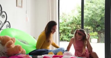 Çeşitli anne ve kız çocukları ellerinde akıllı telefonlarıyla yatak odasına giriyor kıyafet planlama kıyafetlerini düzenliyorlar. Aile, kaynaşma, evcil, neşeli, neşeli, ev, yaşam tarzı