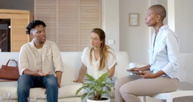 Partide, çeşitli arkadaşlar modern oturma odasında tablet kullanırken fikirleri tartışıyorlar. İşbirliği, teknoloji, beyin fırtınası, arkadaşlık, yenilik, etkileşim