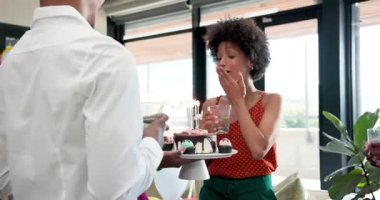 Parlak ofis yerinde veda partisini kutlayan farklı genç arkadaşlar pasta ve içecekler tutuyorlar. Kutlama, veda, dostluk, takım çalışması, mutluluk, aydınlık, toplanma