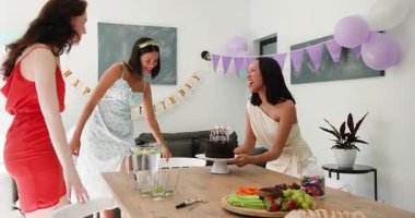 Çikolatalı pasta taşıyan çeşitli bayan arkadaşlar, evde yemek masasında sürpriz doğum günü kutlaması. Kutlama, dostluk, neşe, coşku, kahkaha, sevgi dolu, şenlik