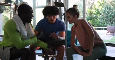 Spor salonunda dambıllarla egzersiz yapan genç bir çift, spor salonuna odaklanıyor. Spor, güç, kaldırma, sağlıklı, motivasyon, eğitim