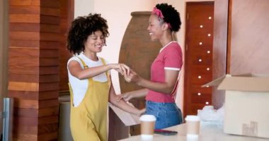 Afro-Amerikan kadınları evde neşeyle dans ediyor, el ele tutuşuyor ve gülümsüyor. Kutlama, dostluk, mutluluk, dans, birliktelik, yurtiçi