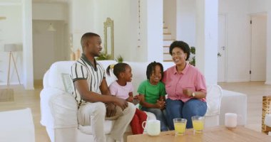 Beyaz evdeki beyaz kanepede etkileşim halinde olan Afro-Amerikan bir aile, neşeli bir enerji gösteriyorlar. Sıcaklık, etkileşim, sıcaklık, modern, oyuncu, ev, birliktelik, aile zamanı.