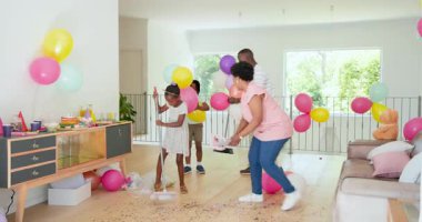 Doğum günü partisini evde canlı balonlar, dağınık konfeti ve atıştırmalıklar arasında kutlayan bir aile. Kutlama, neşe, şenlik, aydınlık, atıştırmalıklar, toplanma, çocuklar, neşeli, neşeli