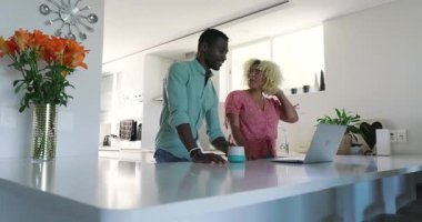 Modern mutfakta, çeşitli çiftler dizüstü bilgisayar kullanıyor, evde birlikte gülümsüyorlar. Aile, yaşam tarzı, teknoloji, mutluluk, yemek pişirme, ev