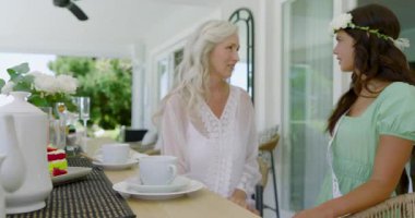 Sunbae, gelininin çiçek tacını kuşağıyla veranda barında selamlıyor ve ayarlıyor. Kutlama, dostluk, aile, zarafet, açık hava, rahatlık, sıcaklık.