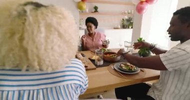 Çeşitli arkadaşlar evde öğle yemeğinin tadını çıkarıyor, kahkahalar ve sohbetler ediyorlar. Arkadaşlık, yemek, sosyalleşme, toplanma, topluluk, kaynaşma