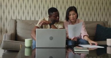 Çeşitli arkadaşlar evdeki proje için dizüstü bilgisayarın çıktılarını incelerken masadan çarşaf alıyorlar. İşbirliği, takım çalışması, gündelik, modern, iç mekan, konsantrasyon, tartışma