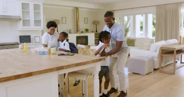Afrika kökenli Amerikalı bir aile, parlak evdeki modern ada adasında ayakkabıların ayarlanmasına yardım ediyor. Aile, ev, çocuklar, yardım, ışık, etkinlik, modern, ev, birliktelik