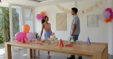 Çeşitli genç erkekler ahşap masa etrafında pasta, balon ve abur cuburlarla parti düzenliyor. Kutlama, şenlik, toplanma, dekorasyon, iç mekan, eğlence, topluluk, parti