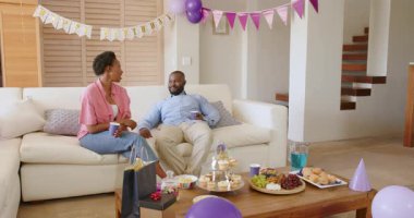 Evde kutlama, çift sıcak oturma odasındaki kanepede atıştırmalık ve içeceklerin tadını çıkarıyor. Rahatlama, birliktelik, yaşam tarzı, boş zaman, kapalı mekanlar, bağ.