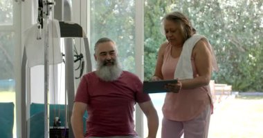 Son sınıf kadın tablet tıkırdatıyor ve ev jimnastik salonunda biseps yapan rehberlik yapıyor. Fitness, strength, motivasyon, training, welness, technology, life style