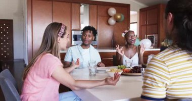 Partide, arkadaşlar yemek masasının etrafında çerez ve içeceklerle sohbet etmekten zevk alıyorlar. Toplanma, sosyalleşme, arkadaşlık, parti, kutlama, kaynaşma