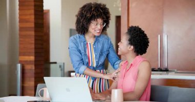 Afro-Amerikalı lezbiyen çift laptopun yanında sevinçle kucaklaşıyorlar, birlikte kutluyorlar. Kutlama, dostluk, mutluluk, birliktelik, teknoloji, bağ