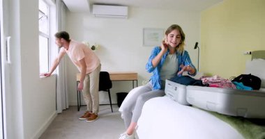 Çift yatakta bavul hazırlıyor, parlak yatak odasında tatile hazırlanıyor, evde. Seyahat, bagaj, hazırlık, yolculuk, macera, yolculuk