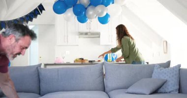 Son sınıf çiftimiz parti popuna tepki veriyor. Kanepeden konfeti süpürüyorlar. Adada doğum günü atıştırmalıkları hazırlıyorlar. Kutlama, yıldönümü, neşeli, rahat, evcil, neşeli, samimi