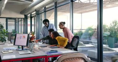 Ofisteki Afro-Amerikalı iş arkadaşları ofis masasında telefon ekranından zaferi kutluyorlar. İşbirliği, takım çalışması, modern, üretkenlik, yenilik, çeşitlilik, başarı