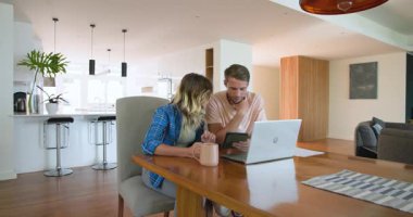 Evdeki çift dizüstü bilgisayar kullanıyor ve kahve içerken planları tartışıyorlar. Yaşam tarzı, teknoloji, iletişim, planlama, gündelik, ilişki