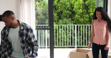 Afro-Amerikalı çift taşınma sırasında sandıkları açıyor, bitki ve sandalyeyi sürgülü kapıların yanına yerleştiriyorlar. İşbirliği, yenileme, yaşam tarzı, iç mekan, tazelik, uyum, uyarılma