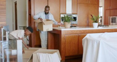 Baba ve oğul mutfaktaki kutuları açıyor, birlikte yeni bir ev düzenliyorlar. Taşınmak, taşınmak, aile, bağ kurmak, takım çalışması, organizasyon.