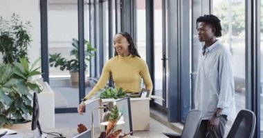 Yeni Afro-Amerikan bir kadınla ofise girerken masanın üstünde kutuları açıyor ve ekip onu selamlıyor. Ofis, çalışma alanı, işbirliği, yeşillik, modern, profesyonel, içişleri