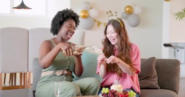 Afro-Amerikalı, Asyalı arkadaşlar oturma odasında kadeh kaldırıyor, doğum günü kutluyorlar. Kutlama, dostluk, tost, modern, rahat, canlı, toplanma, parti