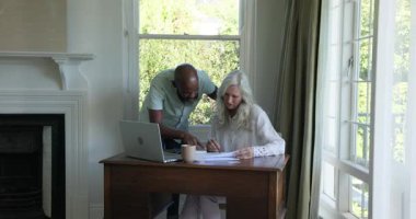 Üst düzey kadın çizelgeleri inceliyor, bilgisayarı masasında Afro-Amerikalı bir adamla birlikte giriş ve iş birliği yapıyor. İşbirliği, akıl hocalığı, takım çalışması, bilgi paylaşımı, kurumsal, modern, profesyonel