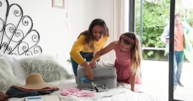 Çeşitli aileler bavullarını yatak kapağının üzerine topluyor. Kahkahalar atılıyor, yüzükler tatile gidiyor. Aile, tatil, seyahat, valiz, açık hava, boş zaman, yaşam tarzı.