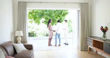 Emlakçı, katlanan kapılarda çiftleri karşılıyor, kontrat imzalıyorlar ve ajans anahtarları veriyor. Mülk, ev sahipliği, ilk kez alıcı, modern yaşam, aile geleceği, profesyonel hizmet, konut