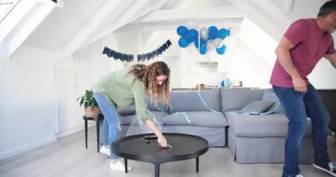 Parti sonrası konfeti süpüren ve tavan arasındaki çöp torbasına flamalar toplayan yaşlı çift. Kutlama, takım çalışması, yerli, gündelik, yenileme, birliktelik, yaşam tarzı