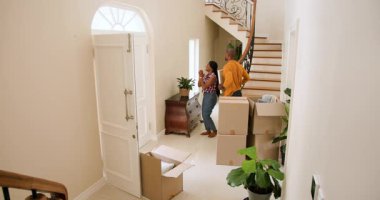 Mutlu siyahi kadın ve erkek, güneşli bir günde yeni bir eve taşınıp duvardaki karton kutuları değiştiriyor. Yeni ev, mülk, mutluluk, yaşam tarzı ve ilişki kavramı.