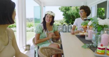 Gelin adayının konuşmasına verandadaki pasta standında el çırparak cevap veren çeşitli bayan arkadaşlar. Kutlama, dostluk, açık hava, zarafet, eğlence, mutluluk, sofistike