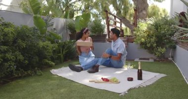 Çeşitli çiftler bahçede yıldönümlerini kutluyor, hediyelerini paylaşıyor ve meyve kesiyor. Kutlama, çift, bahçe, birliktelik, neşe, açık hava, romantizm, doğa