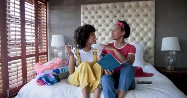 Yatakta oturup kitap okuyan, evdeki mutlu anlarını paylaşan çeşitli kadın çiftler. Yaşam tarzı, rahatlama, birliktelik, bağlanma, ilişki, eğlence.