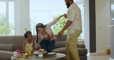 Çeşitli aile dansları, modern oturma odasında doğum günlerini taç ve sarı elbiseyle kutlamak. Kutlama, neşe, aile, mutluluk, canlı, modern, birliktelik