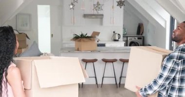 Çeşitli çiftler mutfağa kutu taşıyorlar, taşınmayı kutluyorlar, sarılıyorlar, kolye ışıklarını gösteriyorlar. Çatı katı, daire, yenileme, kutlama, iç mekan, ev, yaşam tarzı