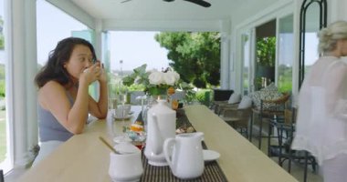 Sunucu balkona pasta koyuyor pasta topluyor ve şarap dağıtırken şampanya içiyor. Eğlence, kutlama, açık hava, brunch, neşe, zarafet, arkadaşlık.