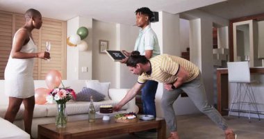 Partide, evde kutlama yaparken, arkadaşlar masayı pasta ve içeceklerle düzenlerken, neşeli hissederken. Kutlama, parti, arkadaşlık, misafirperverlik, toplanma, içecekler