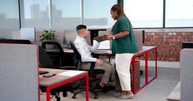 Çeşitli iş arkadaşları modern ofiste bilgisayarlarla ve doğal ışıkla evrak işleriyle ilgili fikirleri tartışıyor. Çalışma alanı, işbirliği, yenilik, üretkenlik, çağdaş, takım çalışması, parlak