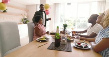 Çeşitli arkadaşlar birlikte yemek yiyor, gülüyor ve evde içkilerimizi yudumluyorlar. Beraberlik, kutlama, toplanma, kaynaşma, yemek, mutluluk