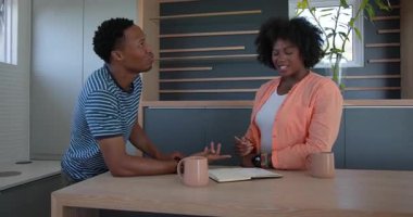 Gülüp eğlenen, evde kahve fincanları olan Afro-Amerikan bir çift. Mutluluk, aşk, ilişki, yaşam tarzı, sabah, rahat